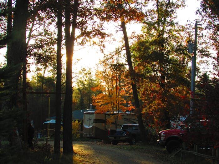 A red truck is parked on the side of the road in the woods