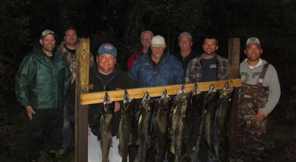 A group of men are posing for a picture with their catch of fish.