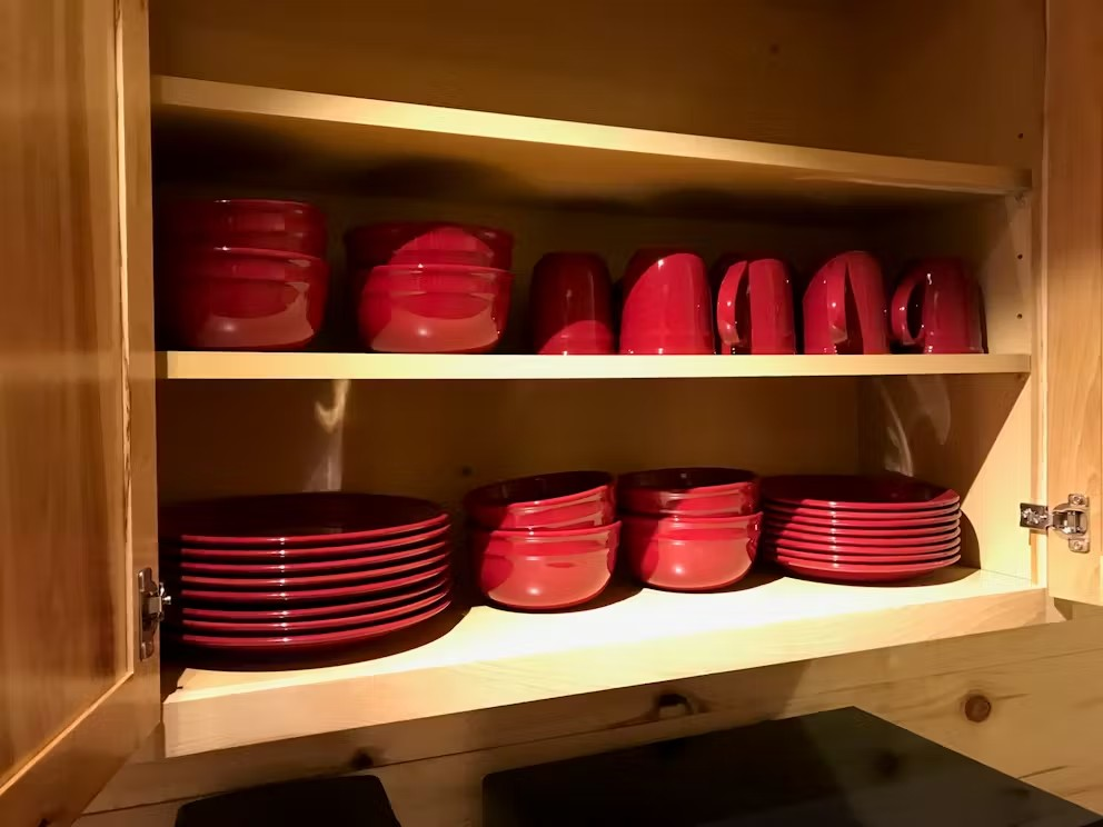 A cabinet filled with red plates bowls and mugs