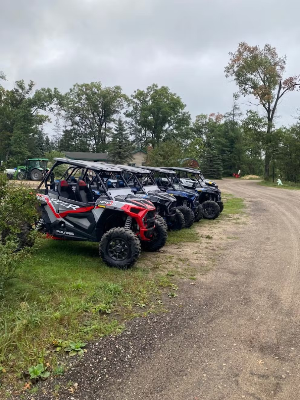 A row of atvs parked on the side of a dirt road.