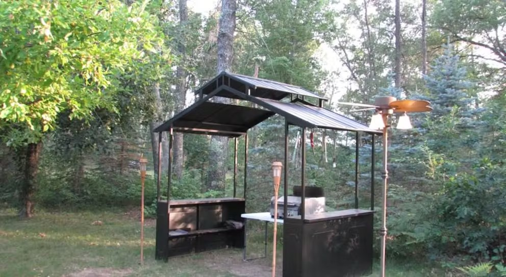 A gazebo in the middle of a forest with trees in the background
