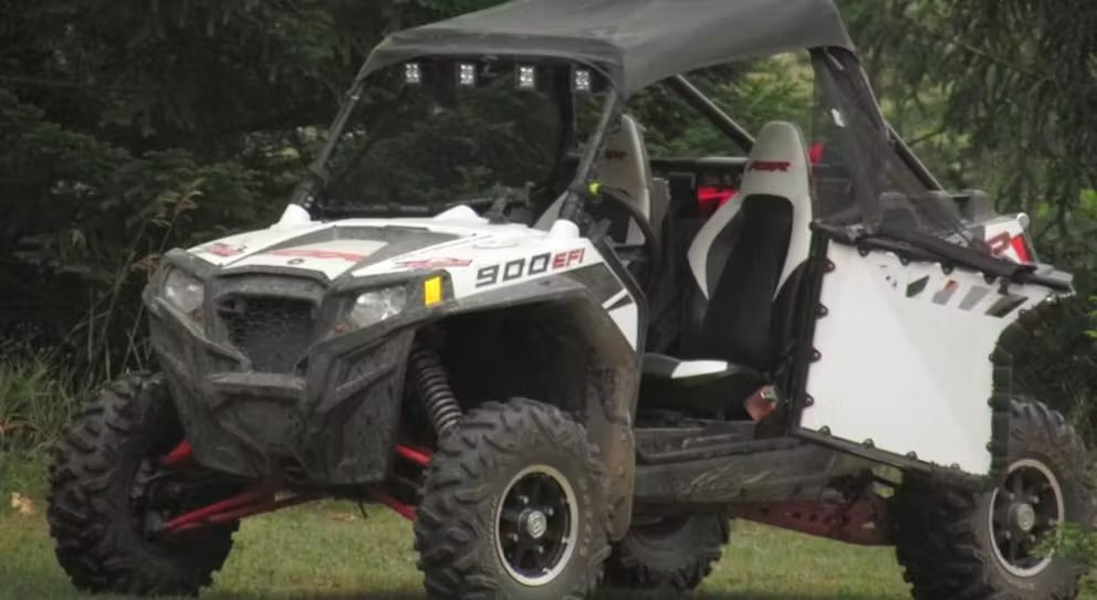 A white and black atv is parked in a grassy field.