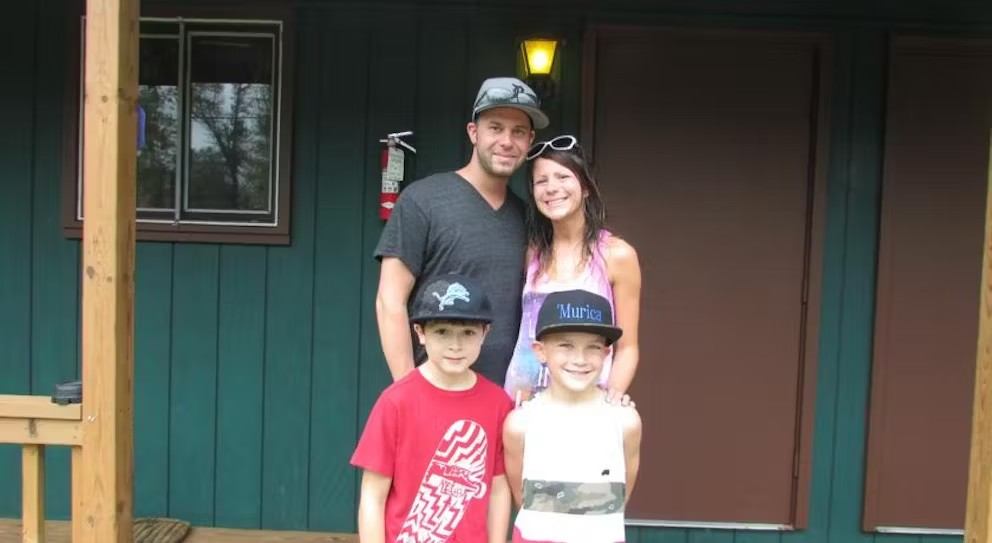 A family is posing for a picture in front of a house.