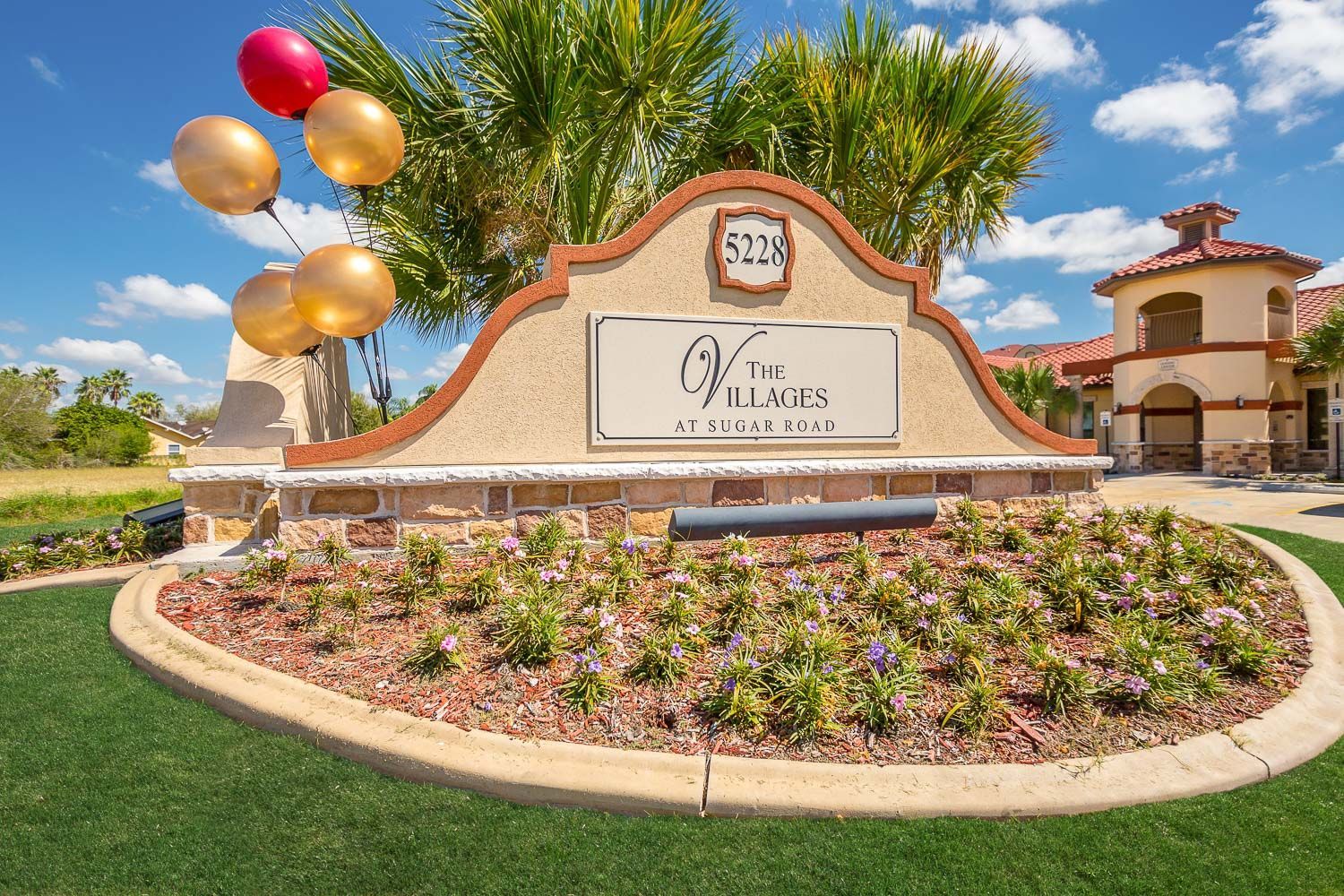 A sign for the villages is surrounded by flowers and balloons.