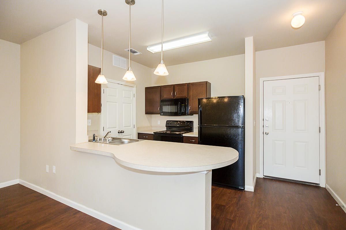 A kitchen with a black refrigerator , stove , microwave and sink.