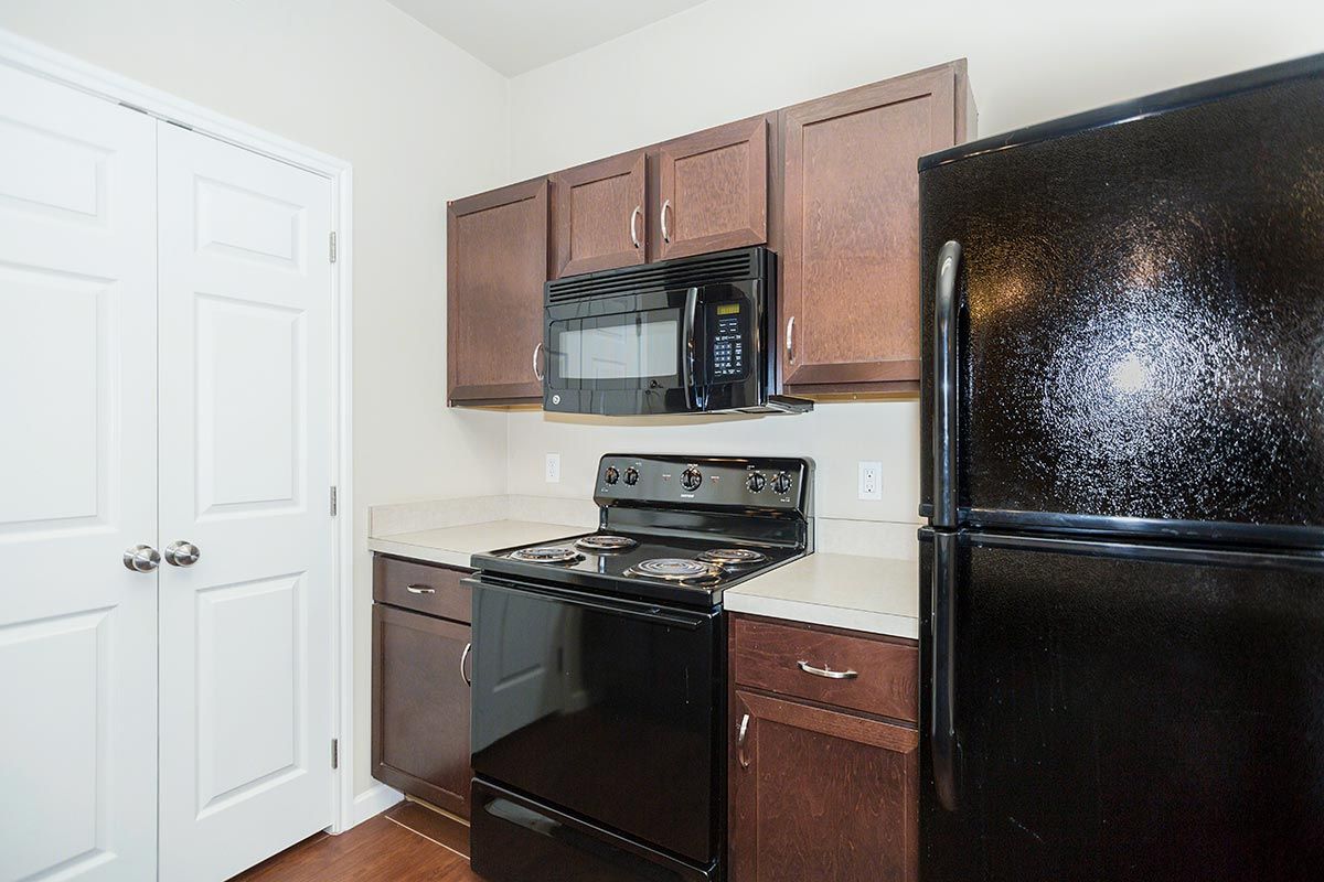 A kitchen with a black refrigerator , stove , microwave and cabinets.