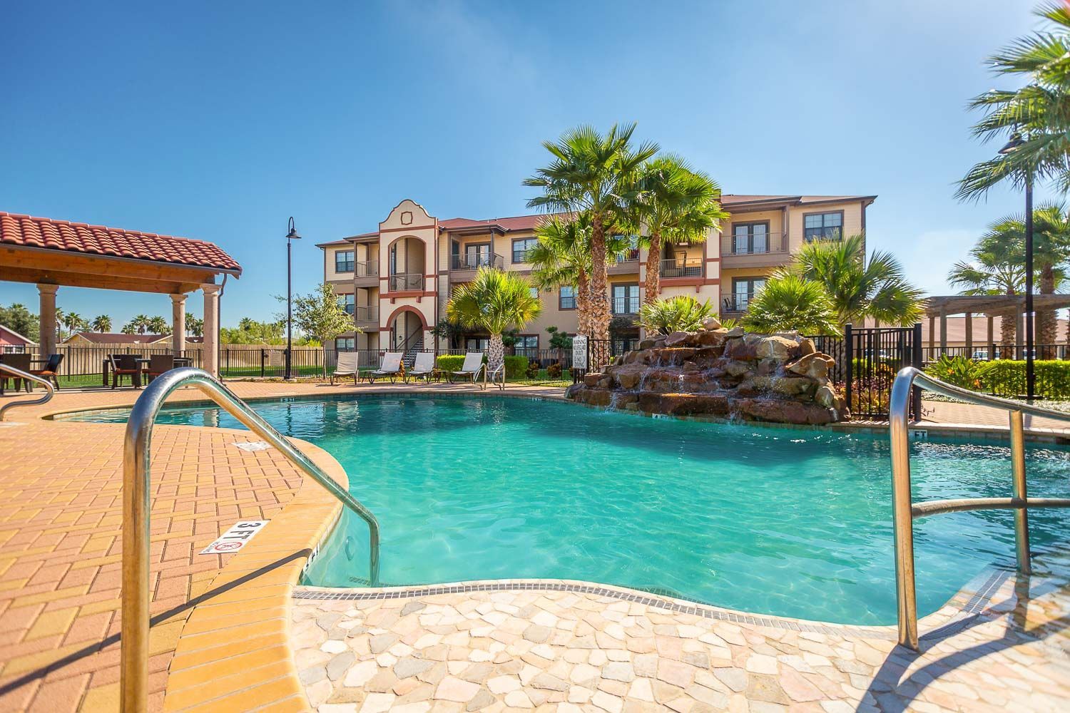 A large swimming pool with stairs leading to it in front of a building.