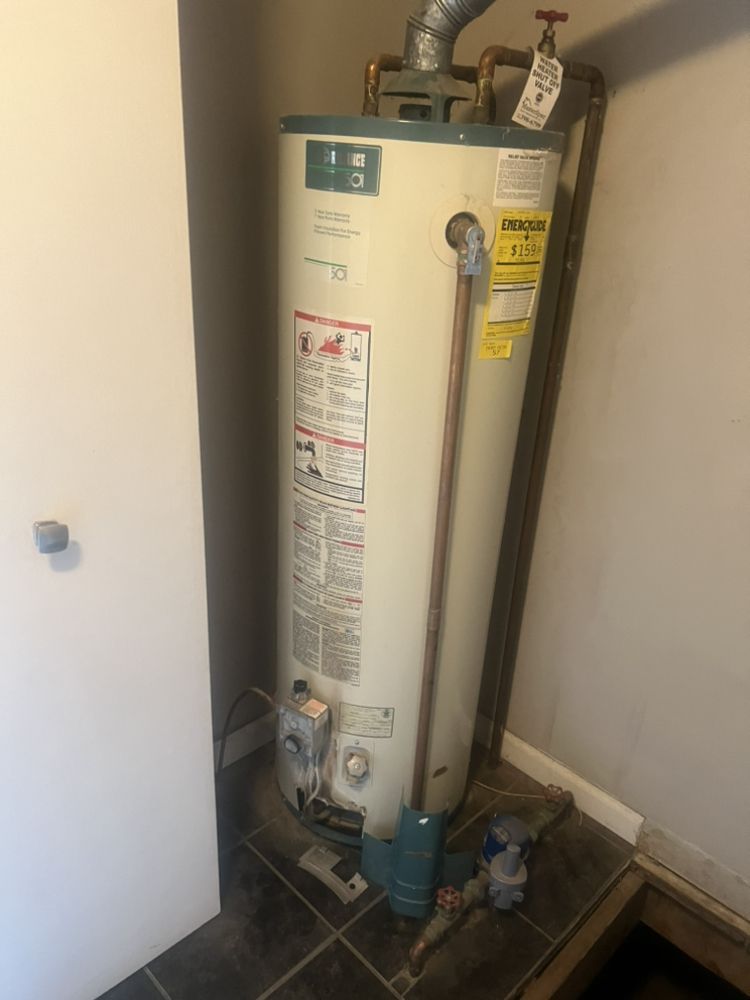 A water heater is sitting in a room next to a door.