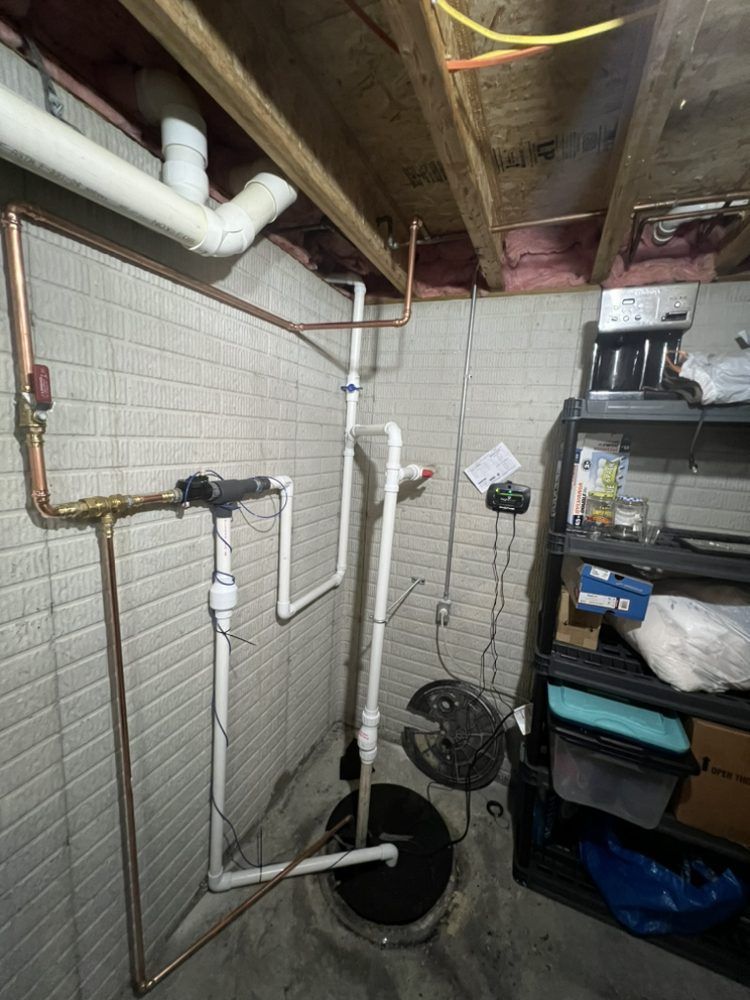 A basement with a sump pump , pipes , and a fan.