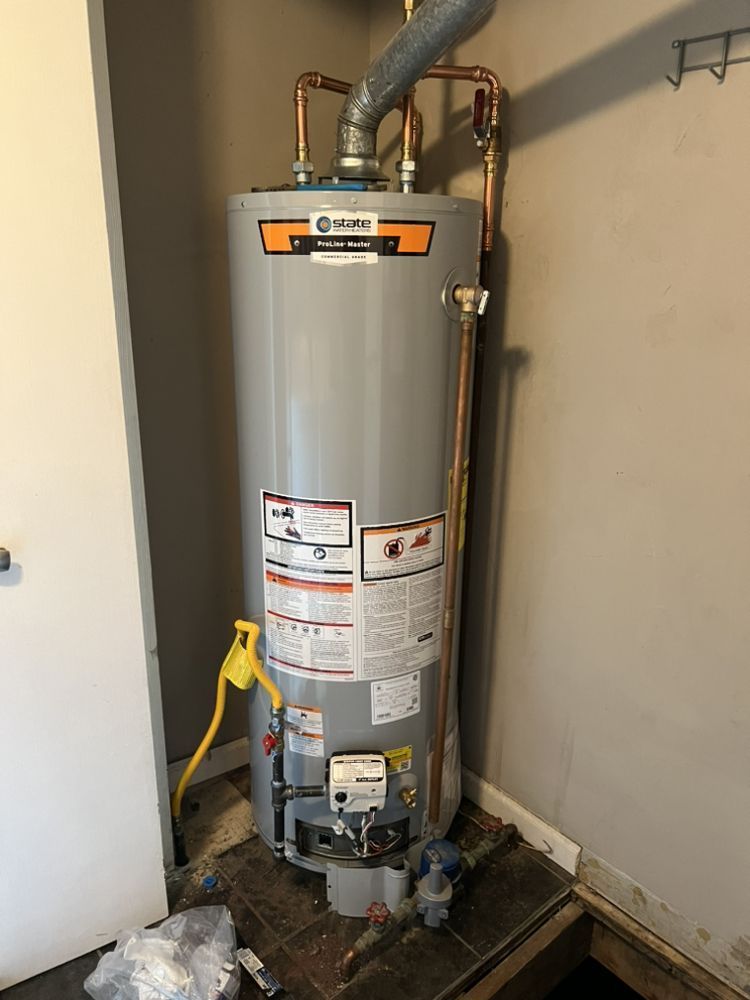 A water heater is sitting in a corner of a room.