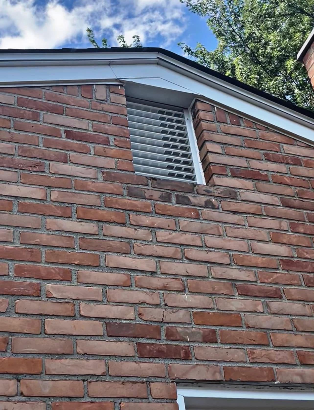 A brick patio with a herringbone pattern in front of a brick house.
