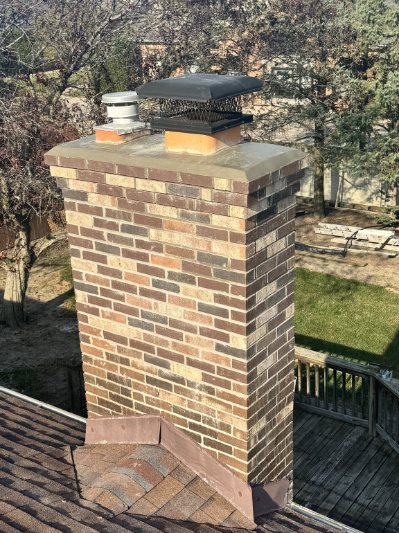 A brick chimney is sitting on top of a roof.