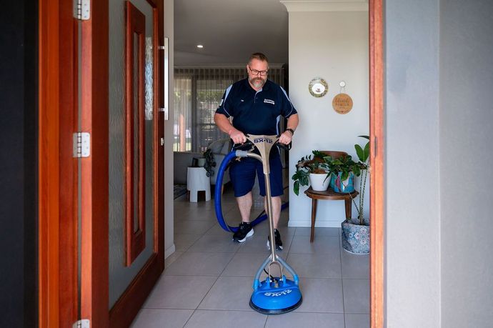 Tile cleaning man cleaning a tiled floor in a blue uniform