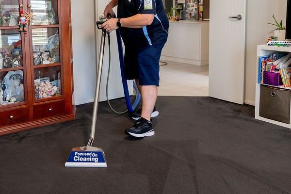 Carpet cleaning man cleaning a brown carpet in a blue uniform