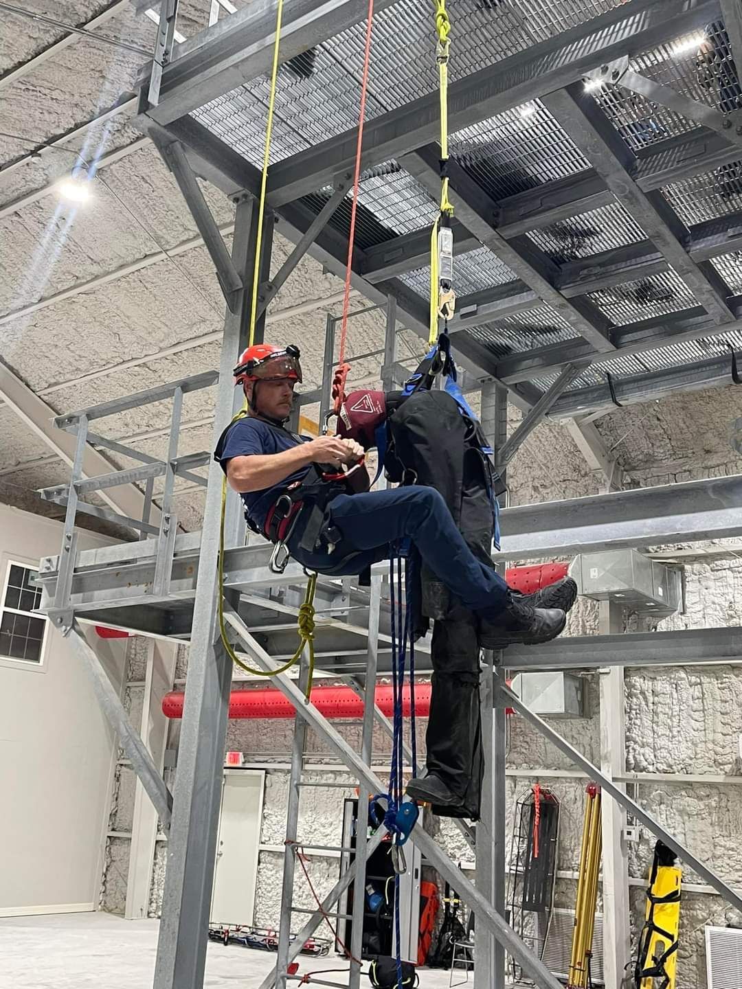 A man is sitting on top of a metal structure in a building.