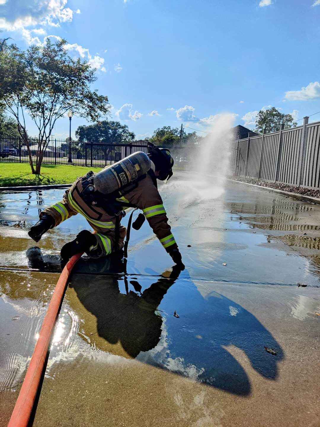 A firefighter is spraying water from a hose on the ground.