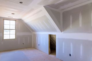 An empty room with a vaulted ceiling and a window.