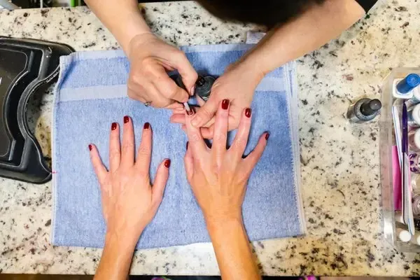 A woman is getting her nails painted at a nail salon.