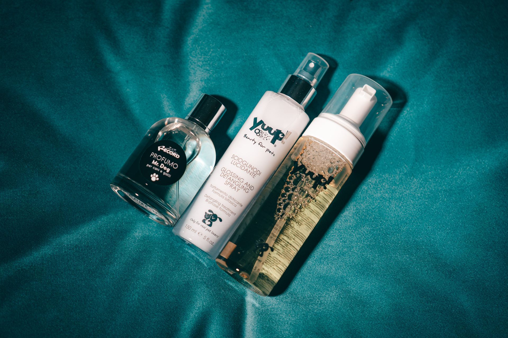 Tre flaconi di prodotti cosmetici su una superficie turchese.