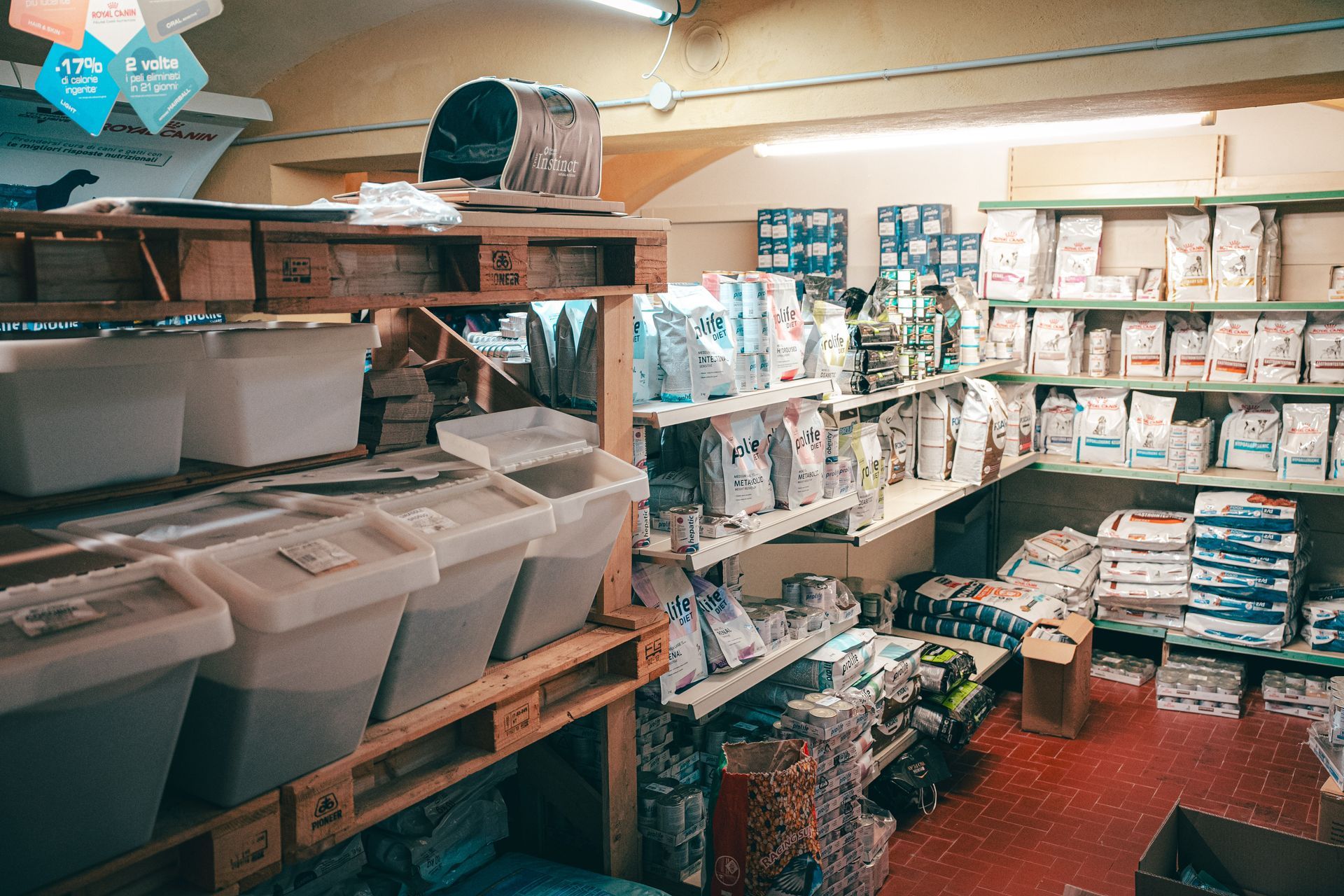 Interno di un negozio di alimenti per animali, scaffali pieni di sacchetti e contenitori di prodotti per animali.