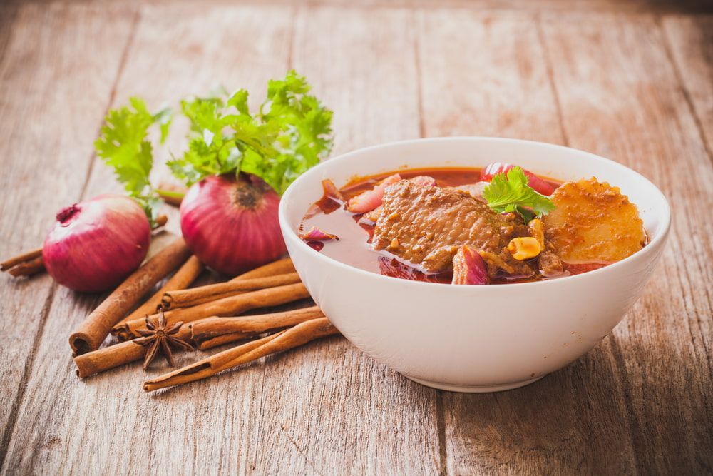 A Bowl of Soup With Meat, Onions and Cinnamon Sticks on a Wooden Table — One Thai Cuisine & Noodle Bar In Kirwan, QLD