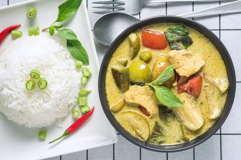 A Bowl of Green Curry Next to a Plate of Rice — One Thai Cuisine & Noodle Bar In Kirwan, QLD