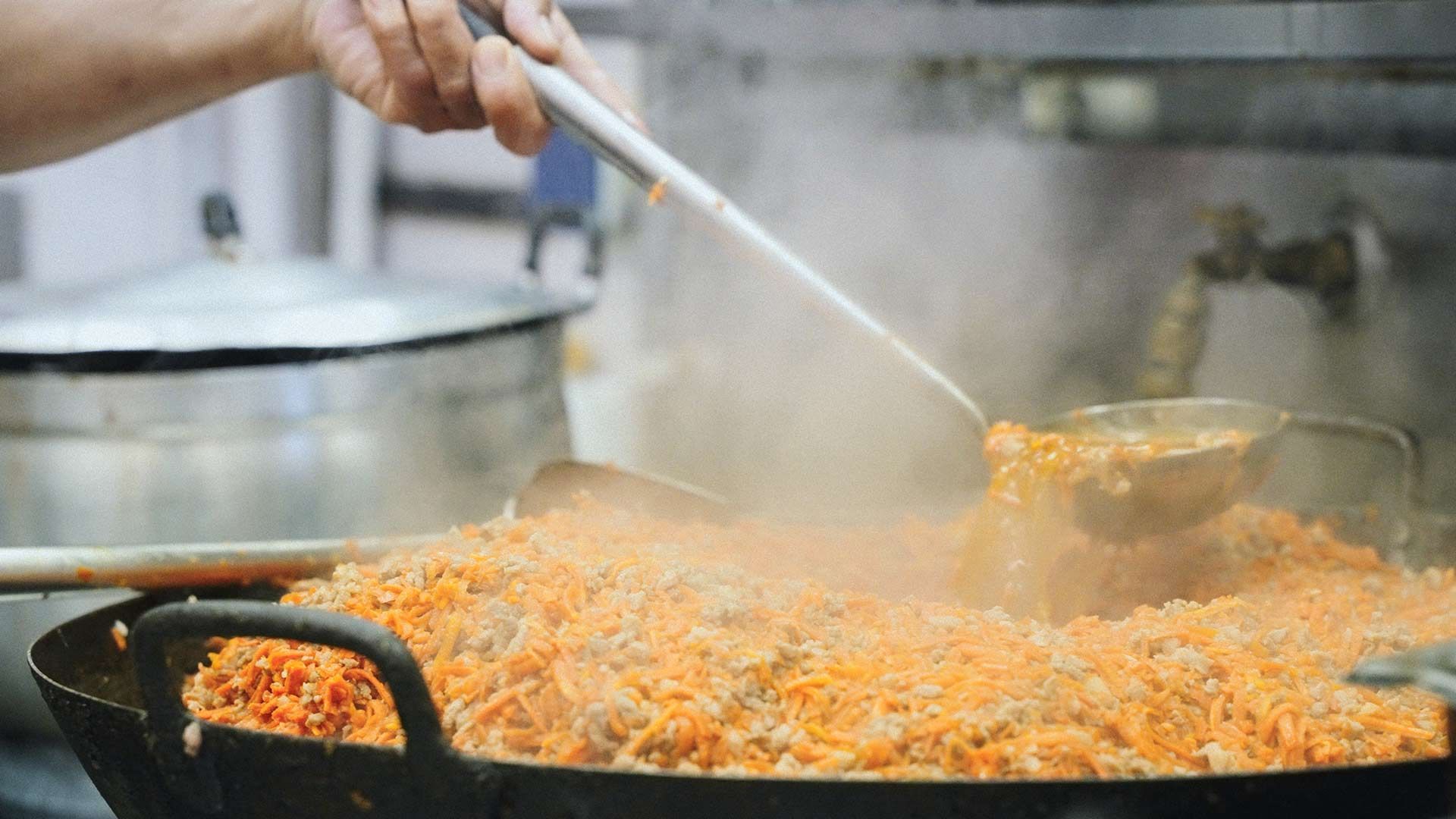 A Person is Cooking Rice in a Pan With a Ladle — One Thai Cuisine & Noodle Bar in Kirwan, QLD