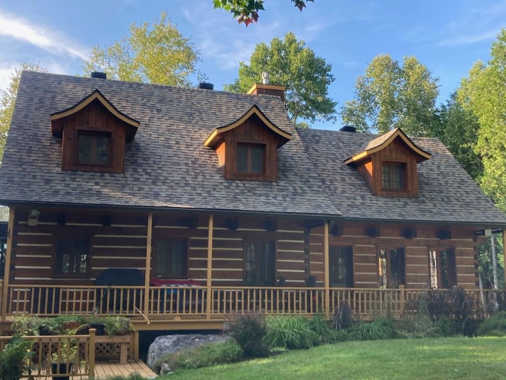 Une grande cabane en rondins avec un porche et un toit en bardeaux