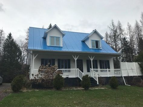 Une maison blanche avec un toit bleu et un porche.