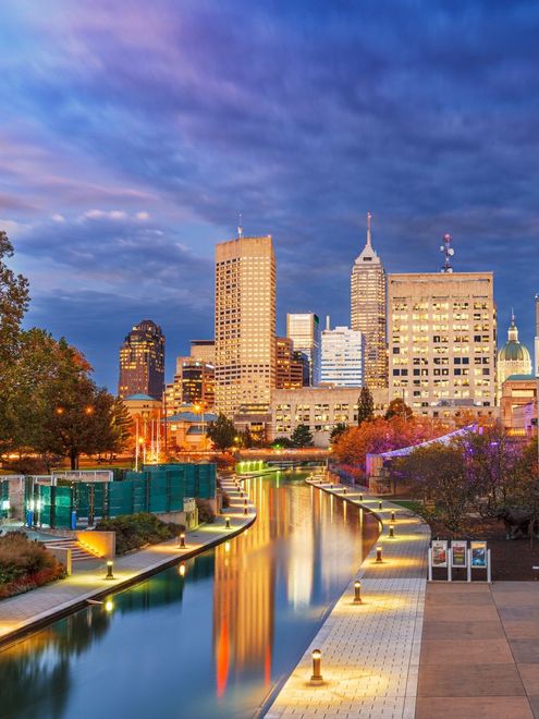 A wooden walkway leading to a gazebo overlooking a body of water at sunset.