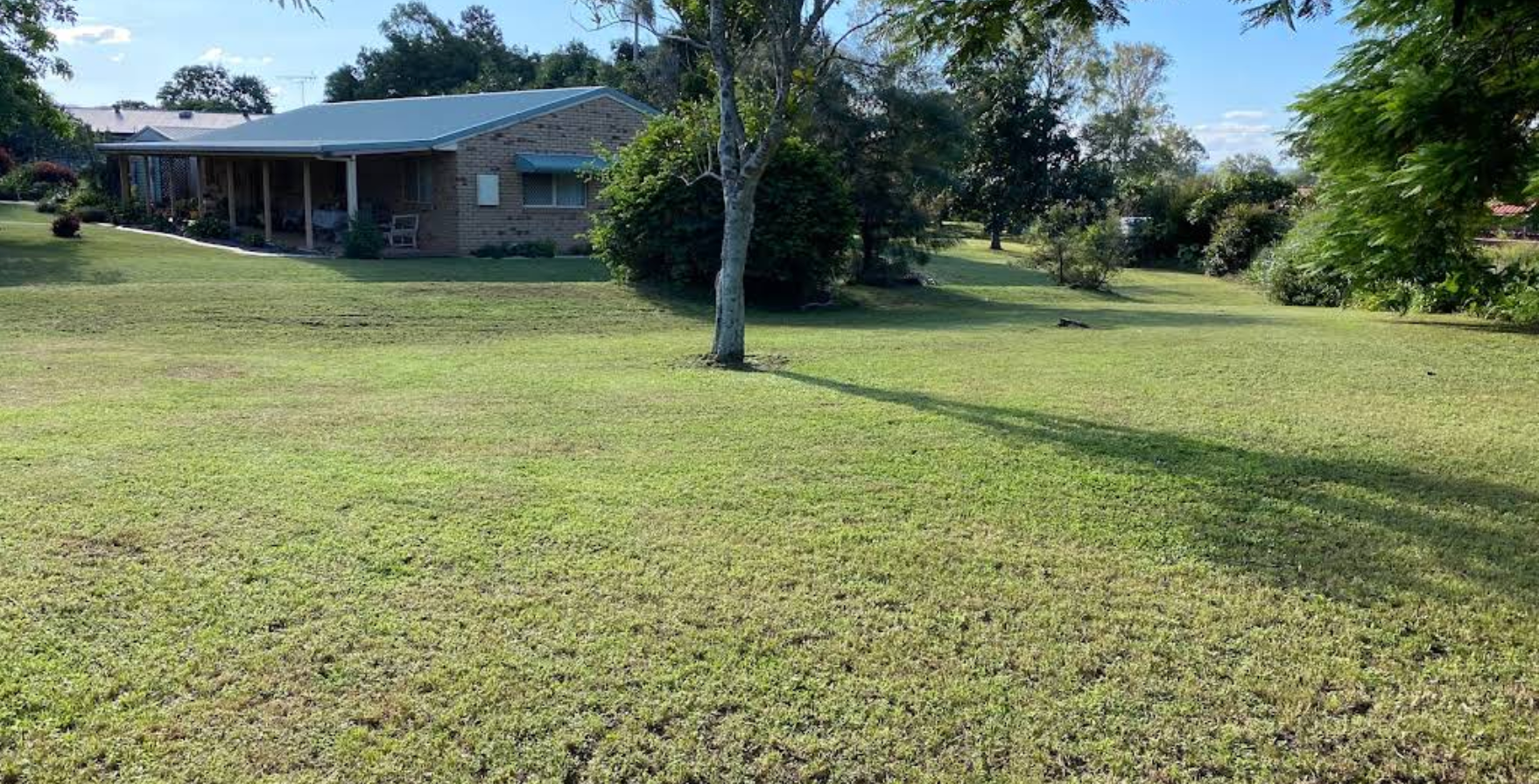 A house with a porch and a large lawn in front of it — Quality Lawns and Gardens in Raworth, NSW
