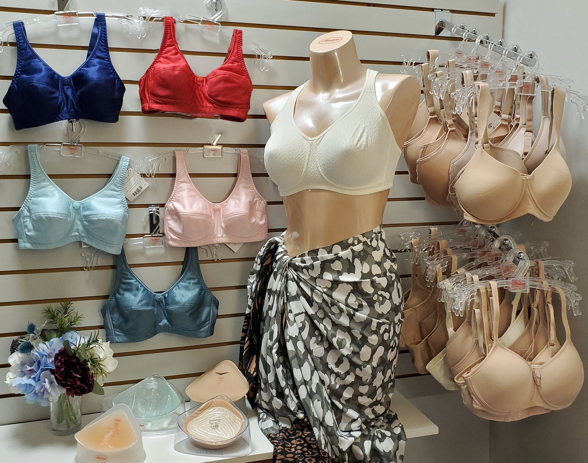 Bras displayed on a wall and mannequin in a store. Various colors and styles.