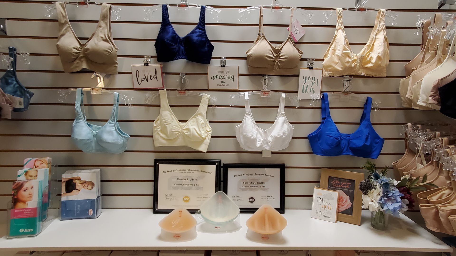 Bras displayed on a wall, with various colors and styles, on a shelf below are accessories.
