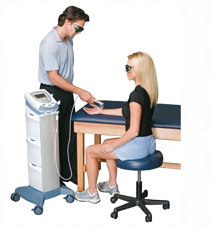 Therapist using laser therapy on a patient's arm. Both wear safety glasses; setting is a medical office.