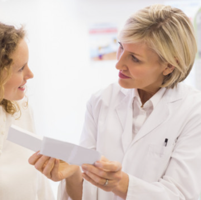 Pharmacist in white coat advising a customer in a pharmacy.