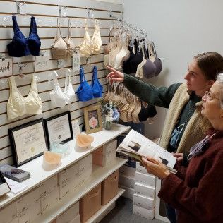 Woman in a cream-colored post-surgical compression bra, smiling. Indoors, sunny.