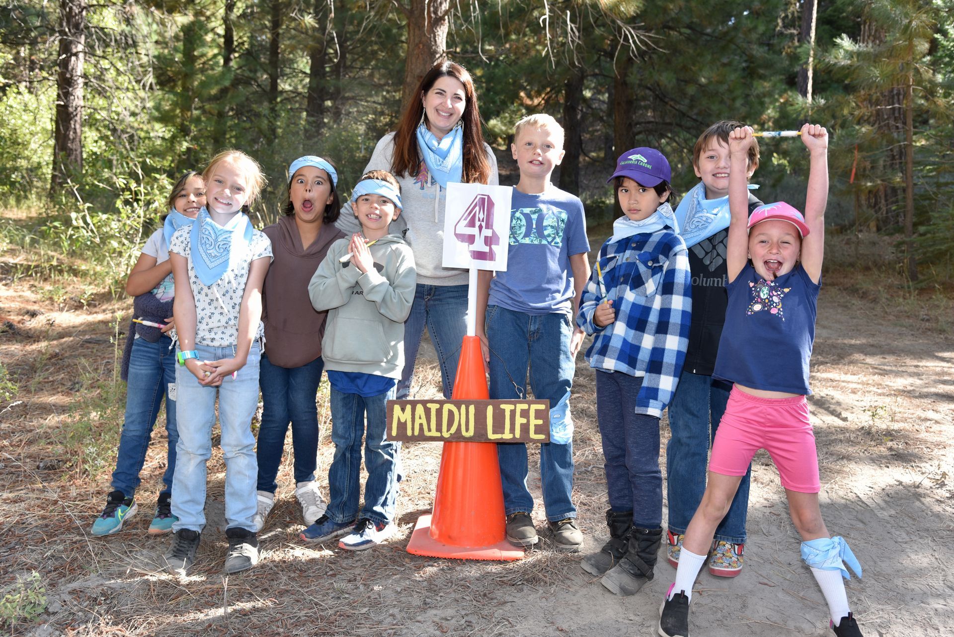 A group of children standing next to a sign that says maidu life
