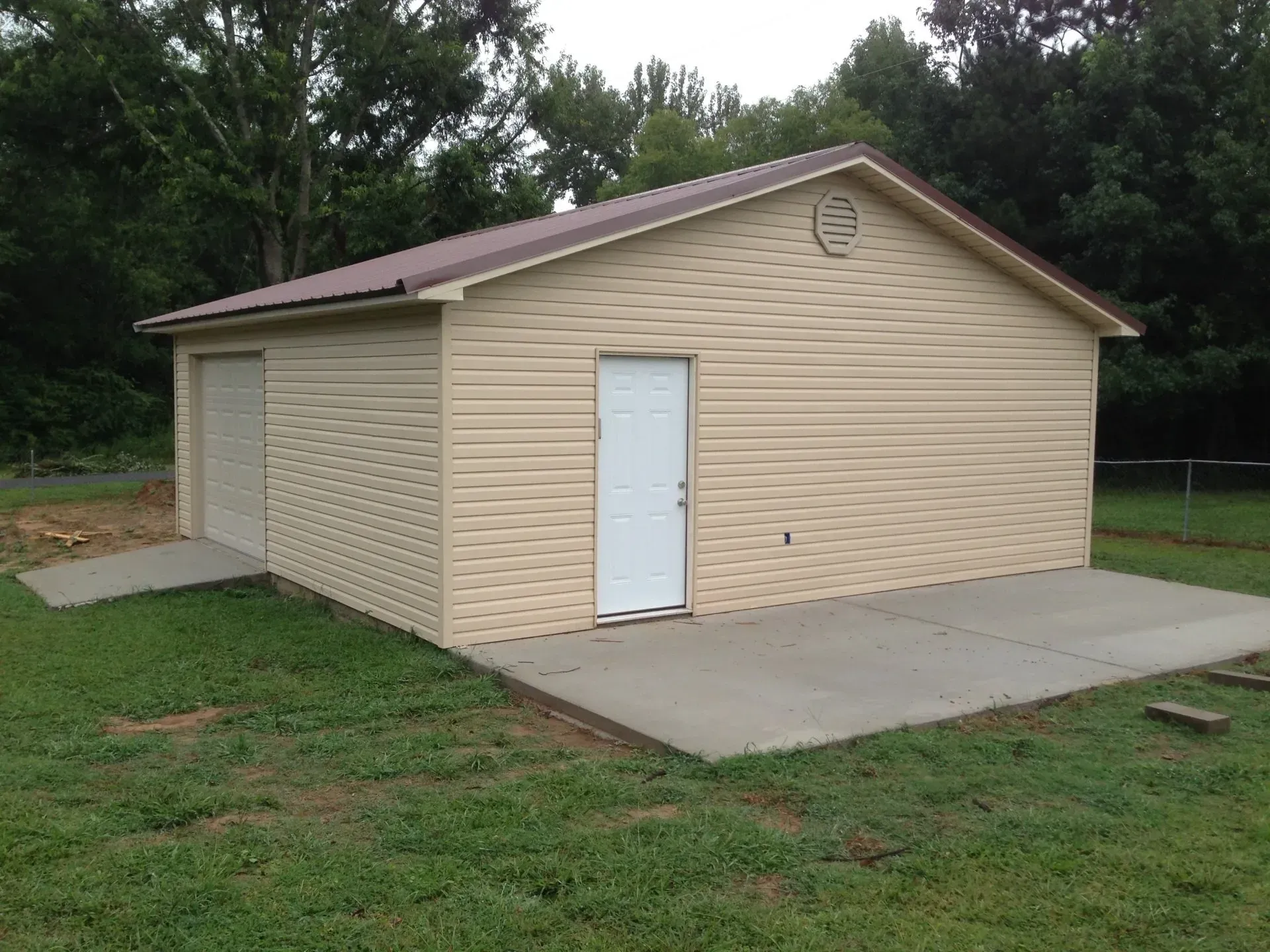 a tan garage with a white door and a brown roof