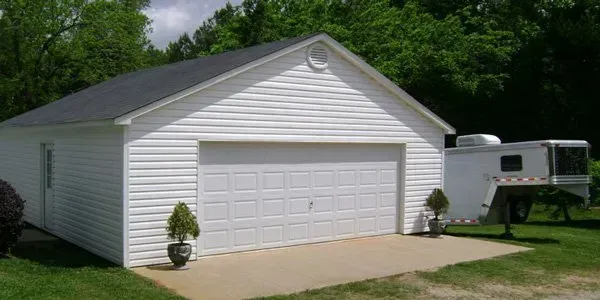 a white garage with a trailer parked in front of it .