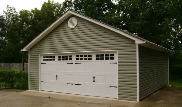 a green garage with white doors and a white roof