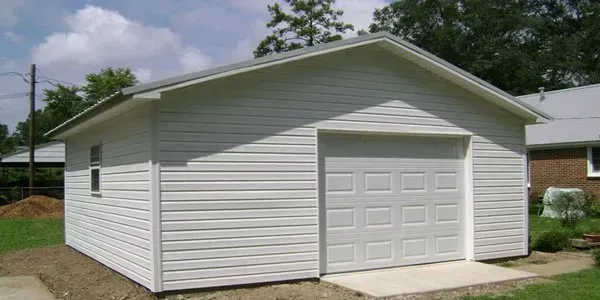 a white garage with a white garage door is in front of a house .