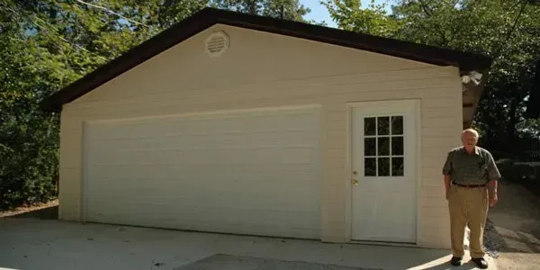 a man is standing in front of a garage with a white door .