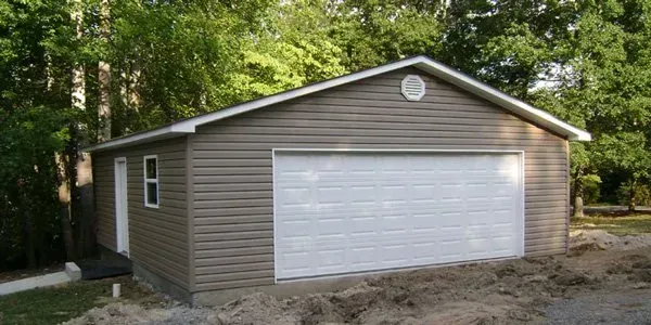 a garage with a white garage door is surrounded by trees .