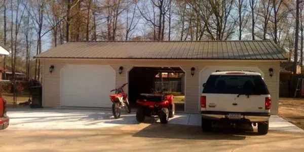 a red atv is parked in a garage next to a white truck .