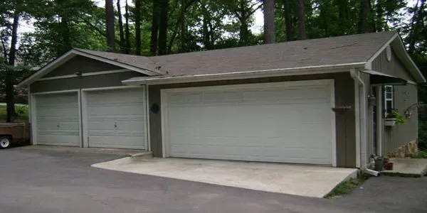 a garage with three garage doors and a truck parked in front of it .