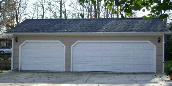 a garage with two white garage doors and a blue roof .