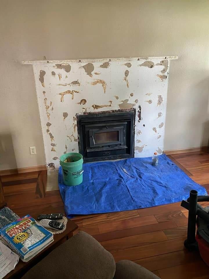 A living room with a fireplace and a blue tarp on the floor.