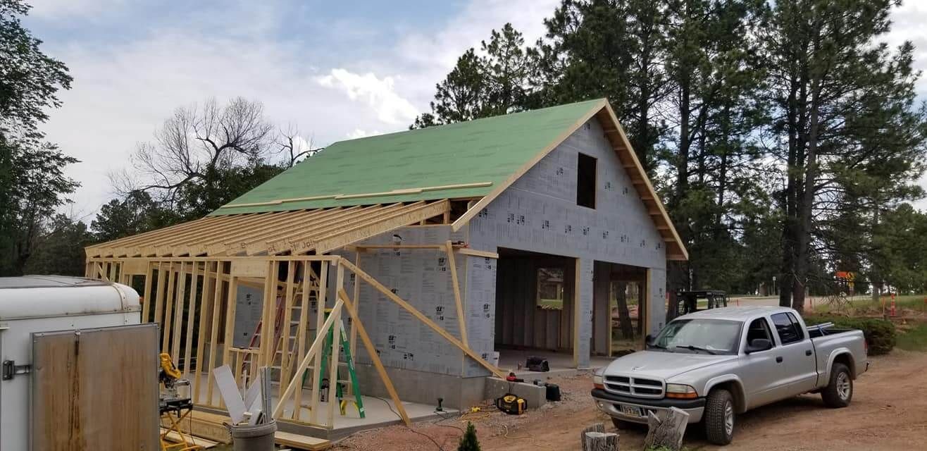 A white truck is parked in front of a house under construction.
