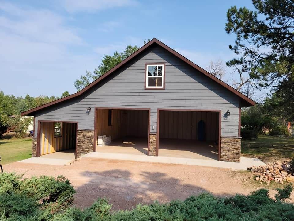 A gray garage with a brown roof and a window