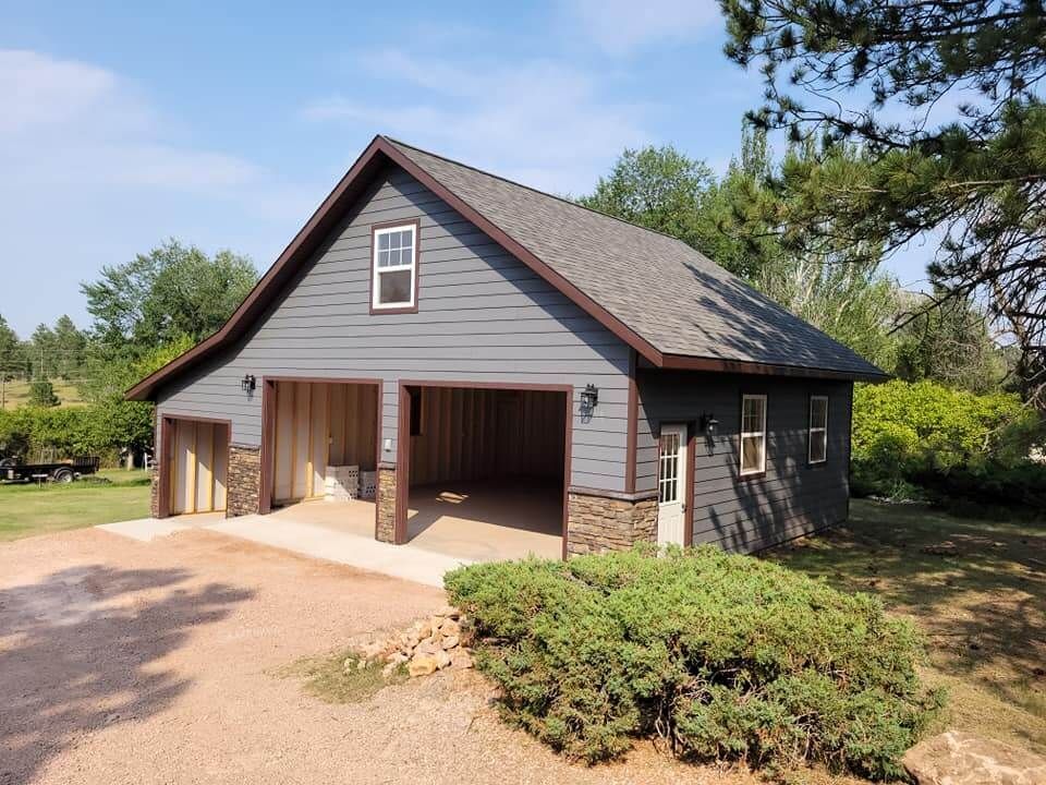 A gray garage with a brown roof and a driveway